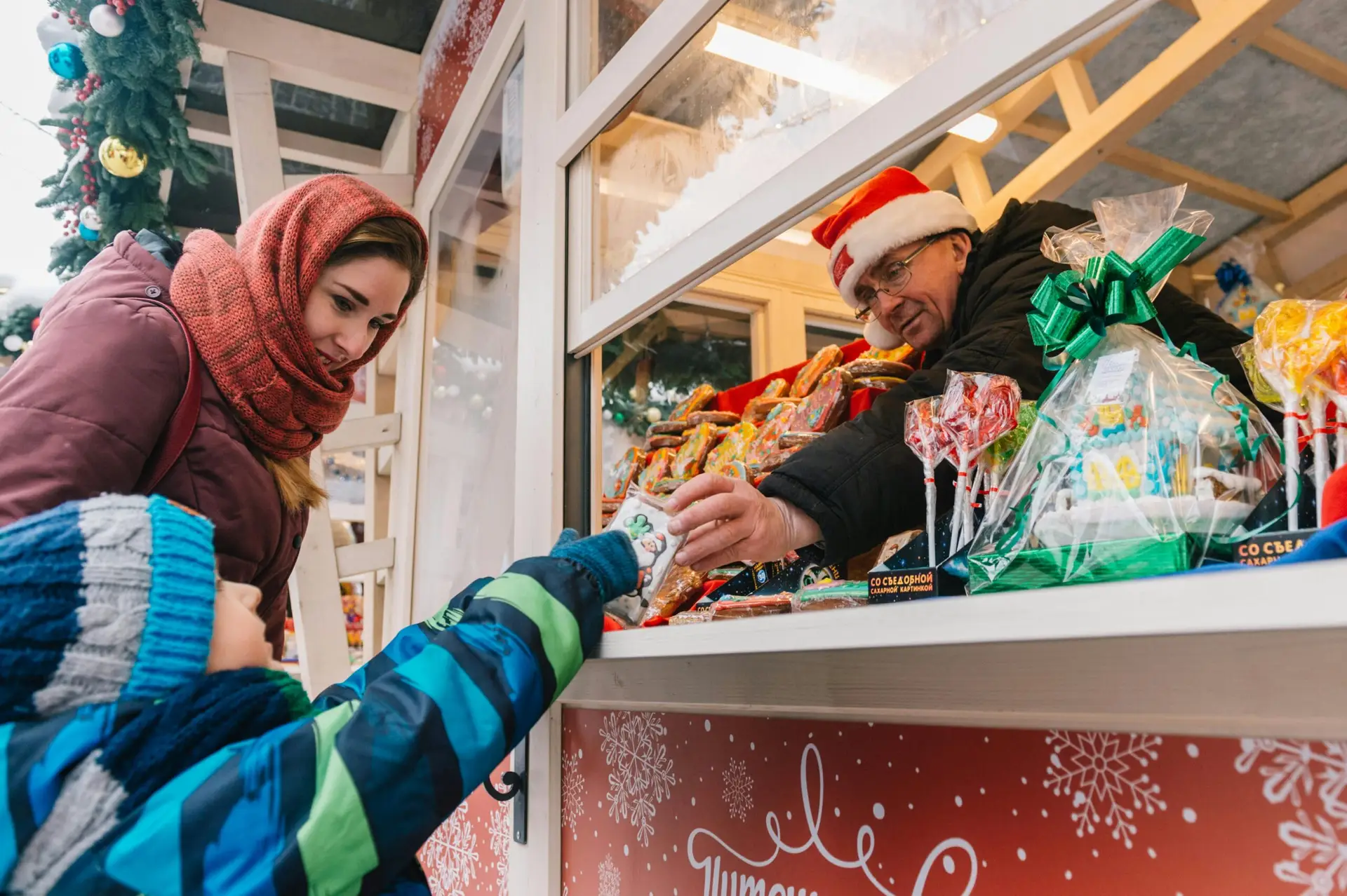 A festive scene of a mother and child selecting sweets from a Christmas market stall.